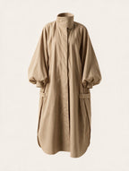 Long oversized puff sleeve trench coat by Elettra Ferri, shown in beige fabric with wide lapels and belted waist.