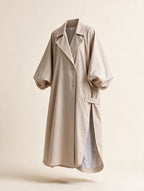 Elettra Ferri long oversized puff sleeve trench coat hanging on a wooden rack, showcasing its stylish design and fabric texture.
